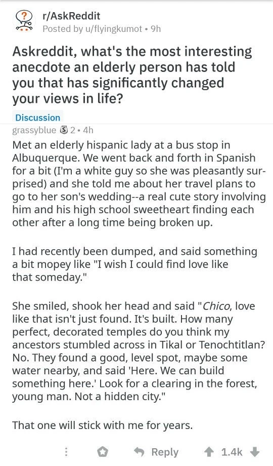 A screenshot of a Reddit post in the r/AskReddit subreddit. At the top it reads “r/AskReddit” and “Posted by u/flyingkumot • 9h.” The question reads: “Askreddit, what's the most interesting anecdote an elderly person has told you that has significantly changed your views in life?” A blue “Discussion” label appears below. The reply is by “grassbyblue,” followed by a small award icon, “2 • 4h.” The reply reads: “Met an elderly hispanic lady at a bus stop in Albuquerque. We went back and forth in Spanish for a bit (I'm a white guy so she was pleasantly sur-prised) and she told me about her travel plans to go to her son's wedding--a real cute story involving him and his high school sweetheart finding each other after a long time being broken up. I had recently been dumped, and said something a bit mopey like "I wish I could find love like that someday." She smiled, shook her head and said "Chico, love like that isn't just found. It's built. How many perfect, decorated temples do you think my ancestors stumbled across in Tikal or Tenochtitlan? No. They found a good, level spot, maybe some water nearby, and said "Here. We can build something here." Look for a clearing in the forest, young man. Not a hidden city." That one will stick with me for years.” At the bottom are Reddit interaction icons, including “Reply,” an upvote count of “1.4k,” and a downvote arrow.